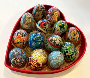 A selection of dyed eggs arranged in a heart-shaped box