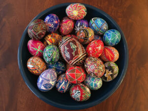 a selection of pysanky, or batik-dyed eggs, in a blue bowl