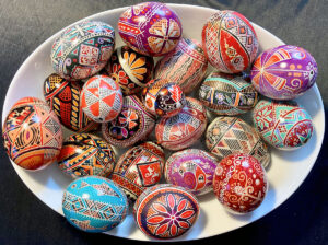 a selection of pysanky, or batik-dyed eggs, in a white bowl