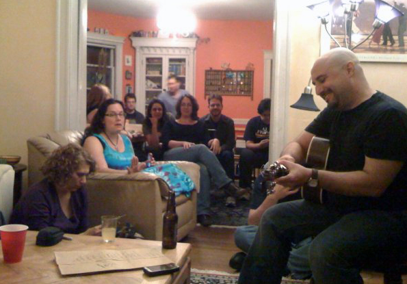 group of people listening to a guitarist.