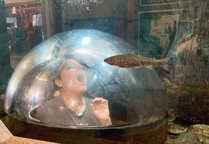 person in pop-up aquarium bubble positioned to look as if a fish is swimming into their mouth